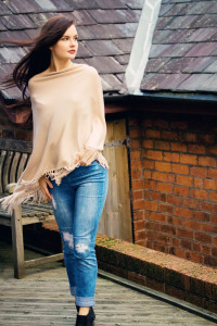 Teen girl wearing beige poncho with ripped jeans