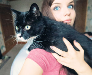 Girl holding black and white cat